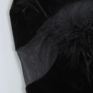 Detail of black velvet mini dress featuring sheer mesh panel and fluffy feather trim