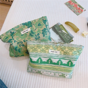 Detail of green floral and yellow striped jacquard fabric makeup bags on a white quilted base