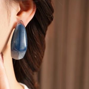 Detail of vintage blue resin teardrop earring with gold leaf flakes worn on ear