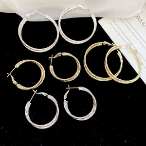 Detail of twisted multi-layer hoop earrings in gold and silver finish on black velvet