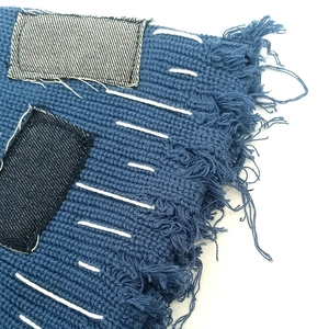 Nahaufnahme der blauen Strickmütze mit Denim-Patch, weißer Naht und Fransen am Rand