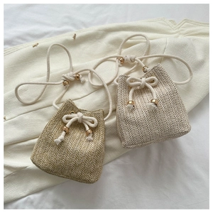 Detailed weave pattern and drawstring closure on beige and tan woven bucket bags