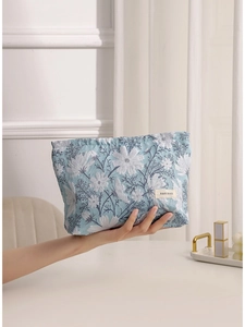 Borsa da trucco jacquard floreale blu e bianca tenuta in un ambiente interno luminoso