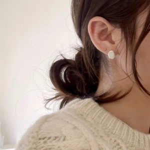 Boucles d'oreilles ovales minimalistes en argent portées par un mannequin dans un style épuré