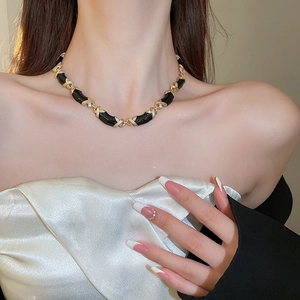 Gros plan d'un collier à maillons croisés en émail noir et plaqué or sur un mannequin