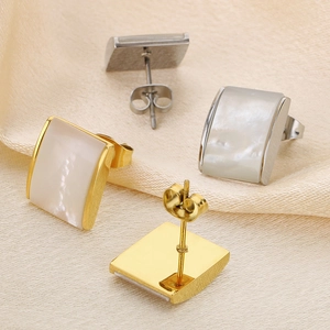 Square stainless steel shell stud earrings in gold and silver set on silk fabric