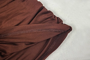 Detail shot of high-quality overlock stitching on a deep brown knitted bodycon dress