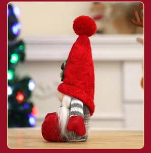 Detail of a Christmas gnome with a red knit hat and white beard on a wooden surface