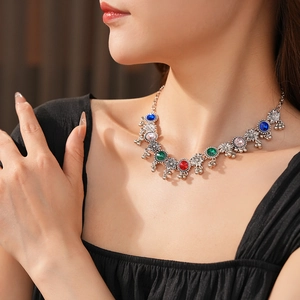 Close-up of vintage silver necklace with colorful gemstones and small bell pendants