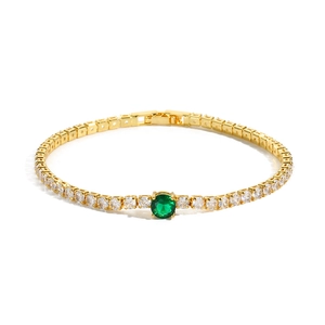 Detail of gold-plated tennis bracelet with clear zircons and green centerpiece