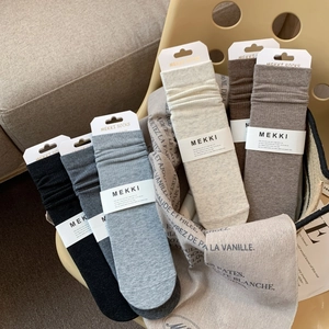 Close-up of assorted earth-tone combed cotton crew socks neatly arranged in a woven basket