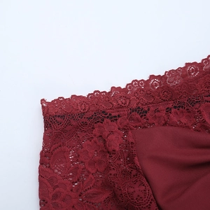 Macro shot of dark burgundy lace edge and woven fabric stitching on a fitted dress