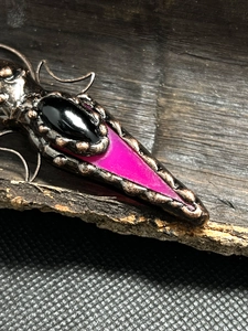 Macro shot of vintage bronze arrow pendant with black agate and raw amethyst stone