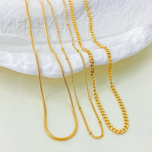 Detail view of four gold-plated chains including snake, satellite, and Cuban links