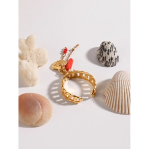 Detail of gold open ring with conch pendant and red bead on sea shell and coral