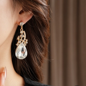 Gros plan de boucles d'oreilles gouttes dorées avec cristaux portées par un mannequin