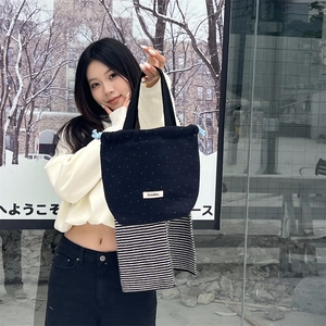 Close-up of black polka dot canvas drawstring handbag with brand label and stripe detail