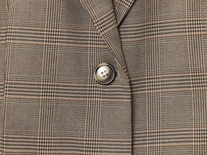 Gros plan sur le tissu à carreaux marron du blazer avec bouton à texture marbrée élégant