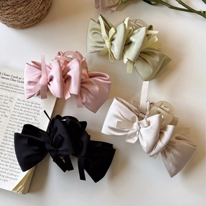 Elegant satin bow hair claw clips in four colors on a vintage French style background