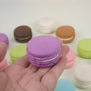 Hand hält einen violetten PU-Squishy-Macaron-Spielzeug mit realistischer Textur und Farben