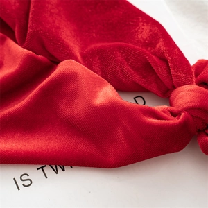 Macro view of soft red velvet texture and detailed stitching on the Christmas scrunchie