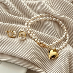 Detail of double-layer pearl necklace with gold heart pendant and matching earrings