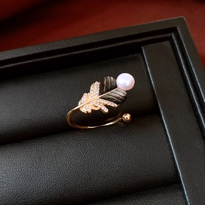 Macro detail of 18k gold plated feather ring with pearl and black inlay on leather