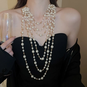 Detailed view of layered pearl necklace with gold beads on elegant model
