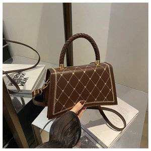 Detail of brown quilted handbag with star patterns and woven gold chain handles