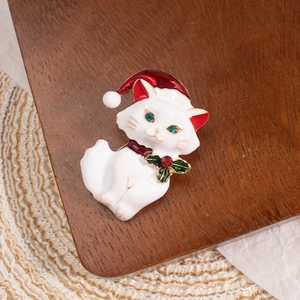 Detail of Christmas cat brooch with white enamel, red Santa hat and green leaf collar