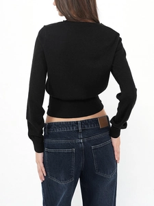Back view of a slim-fit black knit sweater paired with high-waisted dark blue denim jeans