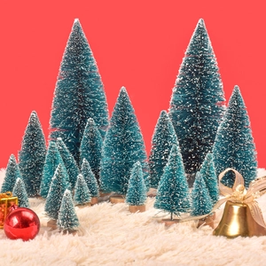 Miniature snow-flocked pine trees in various sizes on soft white faux fur with red backdrop