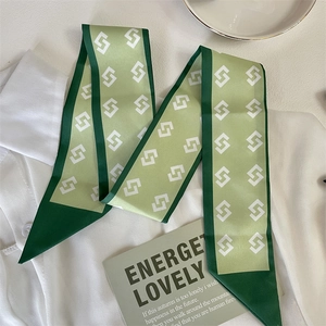 Close-up of green silk scarf with geometric patterns on a white shirt and desk