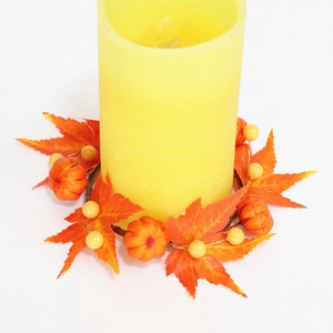 Macro view of fall candle ring with maple leaves, mini pumpkins, and yellow berries