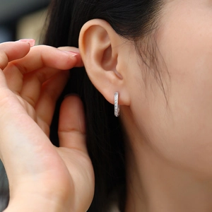 Close-up of minimalist silver hoop earrings with double row sparkling moissanite stones