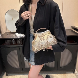 Detailed view of a gold tassel evening bag with shiny sequins and a metal handle