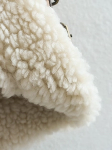 Macro shot of soft white faux shearling fabric texture for women's suede vest detail