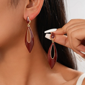 Retro hollow teardrop earrings with dark red enamel in gold finish worn by model