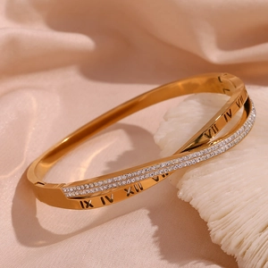 Detail of 18K gold plated bangle with crisscross pave crystals and Roman numeral motifs