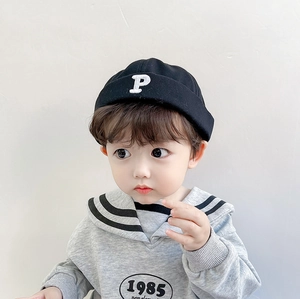 Detail of a black pumpkin hat with P embroidery on a child wearing a gray hoodie