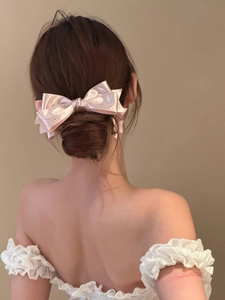 Close-up of pink satin polka dot bow hair clip on a low bun hairstyle