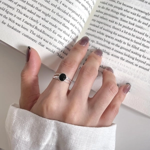 Detail of silver ring with black onyx and vintage hollow texture on fingers with book