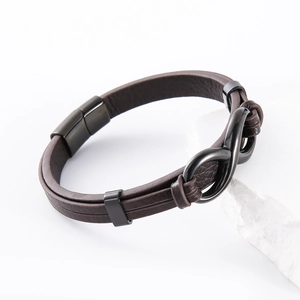Dettaglio macro del bracciale in pelle intrecciata marrone con simbolo infinito nero