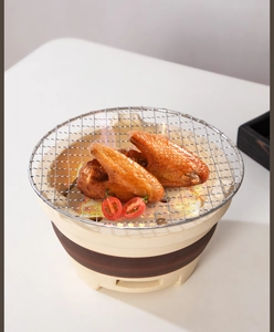 Top view of Japanese ceramic charcoal grill with grilled chicken wings and tomatoes