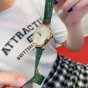 Close-up of women's gold watch with diamond bezel and green leather strap