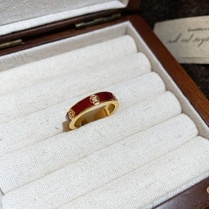 Macro detail of 18k gold plated ring with red enamel and coin charms in a wooden jewelry box