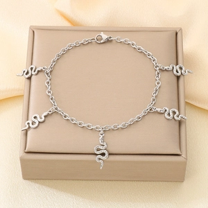 Détail d'un bracelet à breloques serpent en argent sur présentoir en soie dorée