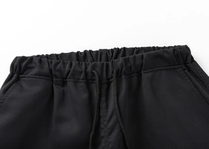 Detail of the elastic waistband and drawstring on black cargo shorts made of twill fabric