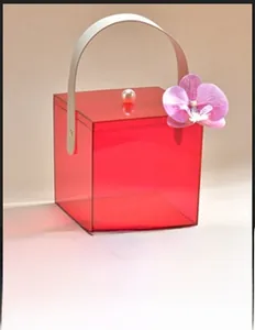 Macro shot of red translucent acrylic gift box with leather handle and orchid detail
