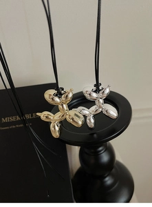 Close-up of gold and silver balloon dog pendants hanging on a black stand in Y2K style